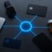 An overhead flat-lay of everyday objects — a smartwatch, a credit card, a prescription pill bottle, a smartphone, a loyalty card, and a laptop — arranged in a circle, each connected by thin glowing lines to a central orb labeled "Your Data." Cool, clinical lighting. Minimalist editorial aesthetic. Muted tones with a single highlight color (electric blue). No text on objects, photorealistic product style.