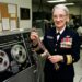 Grace Hopper at her computer terminal with programming code and early computer systems, representing her pioneering role in software development and compiler creation